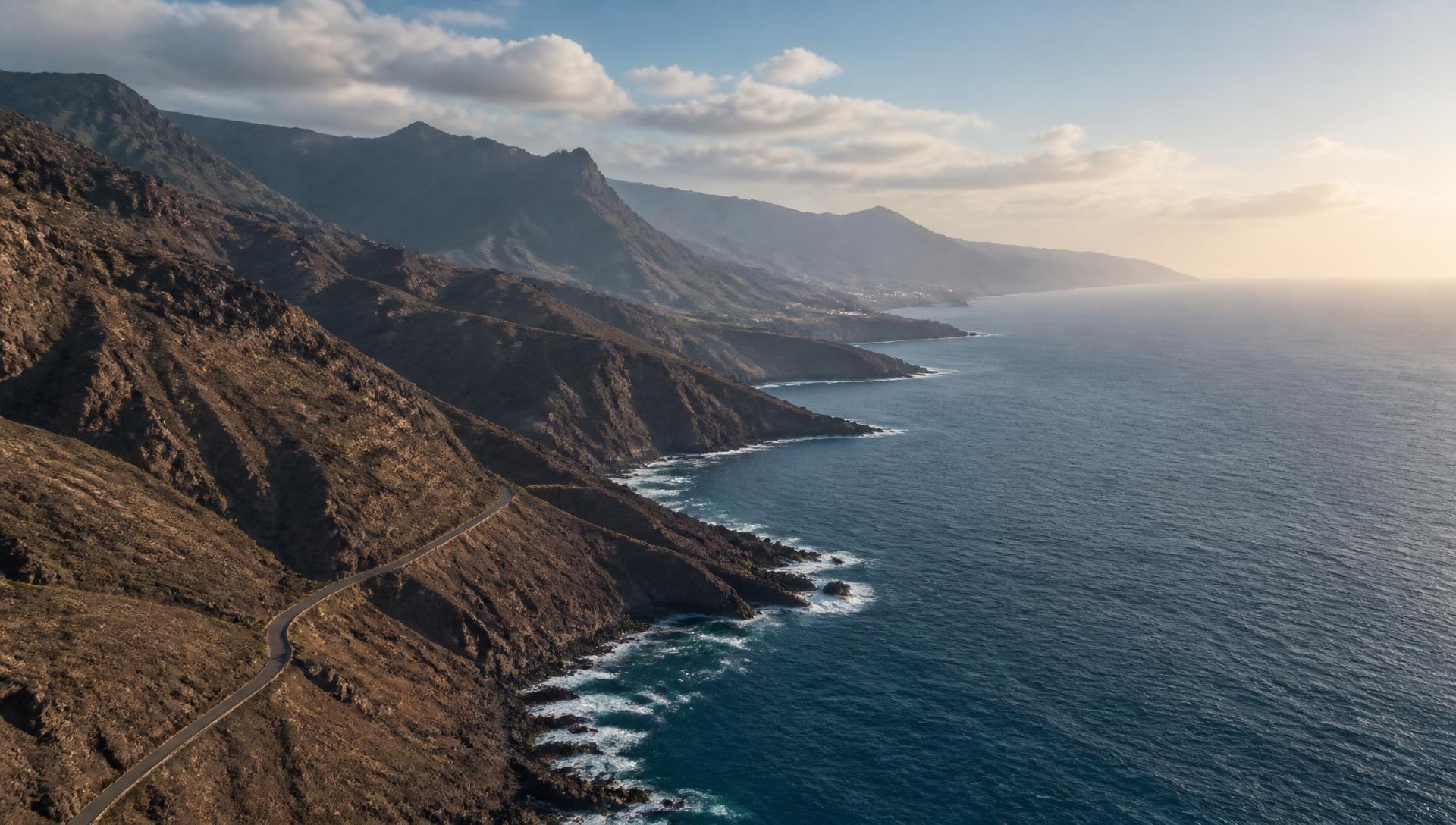 Aerial view of Tenerife's rugged volcanic coast meeting the Atlantic in late afternoon light